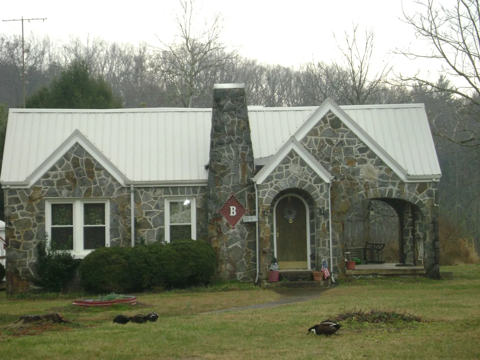 White metal roof on a stone cottage with steep gables in Caledonia